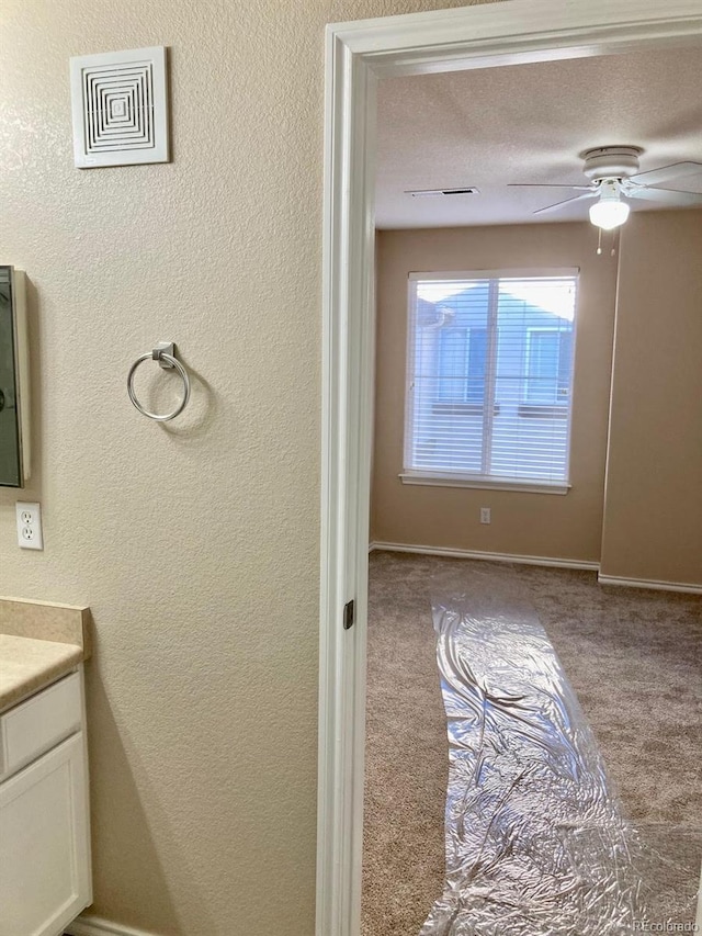 bathroom with ceiling fan, vanity, and a textured ceiling