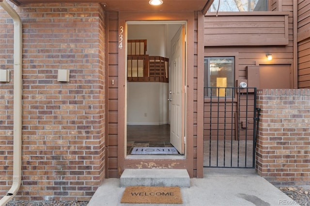 doorway to property with brick siding and a gate