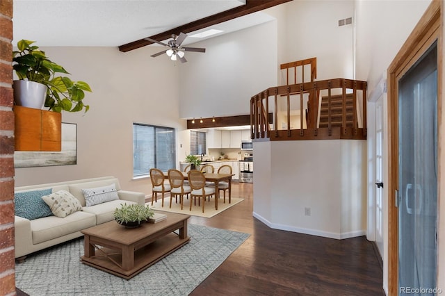 living area featuring a ceiling fan, visible vents, baseboards, dark wood finished floors, and beamed ceiling