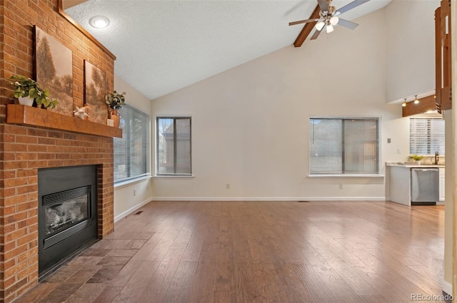 unfurnished living room with baseboards, a ceiling fan, wood finished floors, and a fireplace