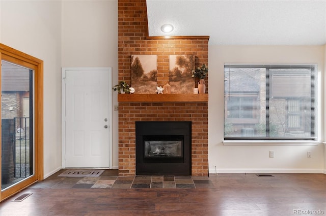 unfurnished living room featuring visible vents, baseboards, wood finished floors, and a fireplace