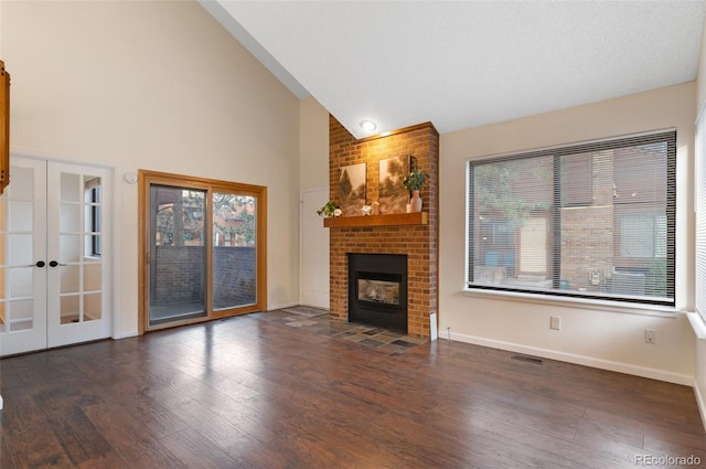 unfurnished living room featuring a brick fireplace, french doors, and wood finished floors