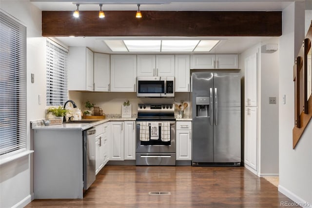 kitchen with visible vents, beam ceiling, a sink, dark wood-style floors, and appliances with stainless steel finishes