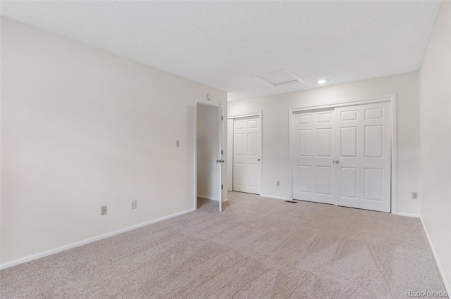 unfurnished bedroom featuring attic access, baseboards, and carpet floors