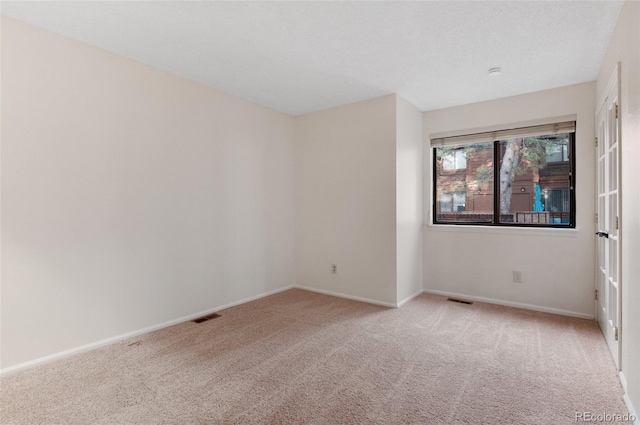 empty room with baseboards, visible vents, and carpet floors