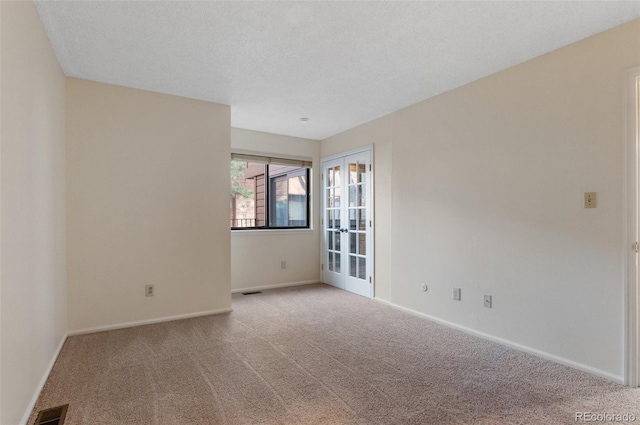 empty room with visible vents, a textured ceiling, french doors, carpet, and baseboards