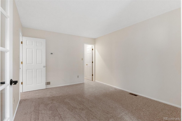 unfurnished room with carpet, visible vents, and baseboards