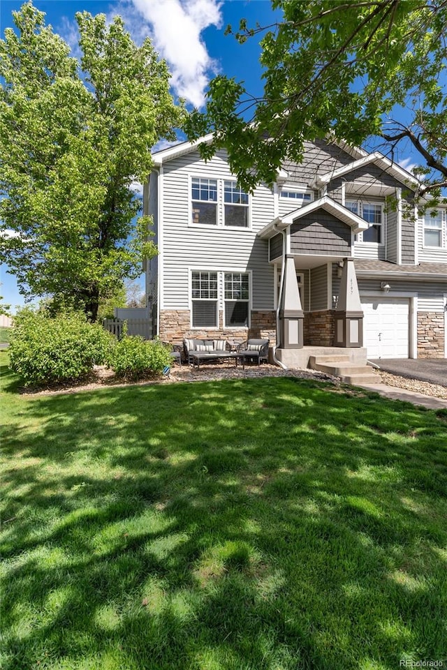 4797 Flower St, Wheat Ridge, CO 80033 - view of front of property with stone siding, a front lawn, a garage, and driveway