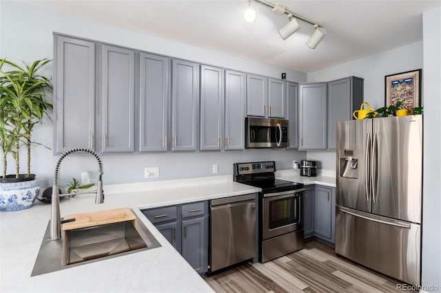 4797 Flower St, Wheat Ridge, CO 80033 - kitchen with appliances with stainless steel finishes, gray cabinets, a sink, light countertops, and wood finished floors