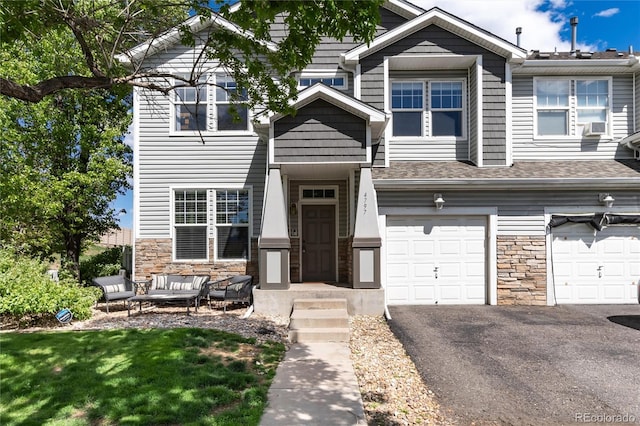4797 Flower St, Wheat Ridge, CO 80033 - view of property with stone siding, a garage, asphalt driveway, an outdoor hangout area, and a front lawn