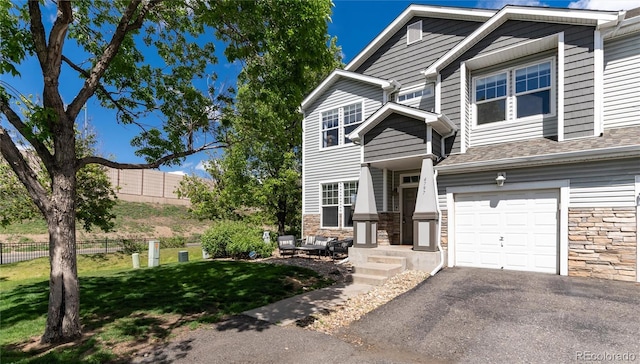 4797 Flower St, Wheat Ridge, CO 80033 - view of front of property featuring stone siding, an attached garage, and driveway
