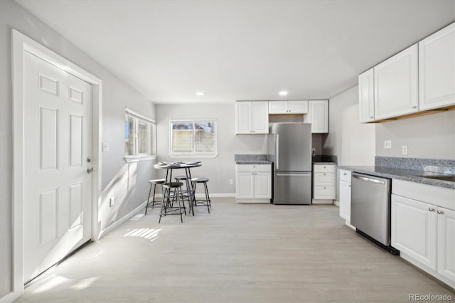 kitchen with white cabinetry, stainless steel appliances, and light wood-type flooring