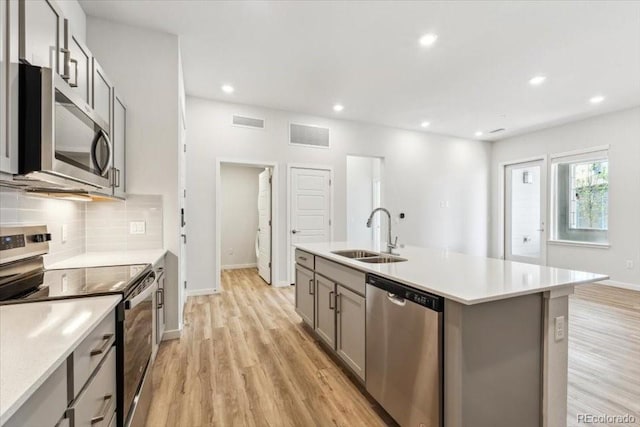 485 Interlocken Blvd Unit 106, Broomfield, CO 80021 - kitchen with appliances with stainless steel finishes, gray cabinets, a sink, tasteful backsplash, and light wood-style flooring