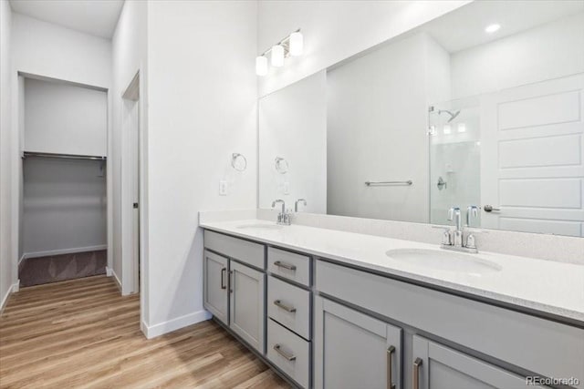 485 Interlocken Blvd Unit 106, Broomfield, CO 80021 - bathroom with double vanity, wood finished floors, a tile shower, and baseboards