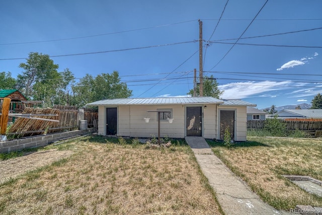 view of front of house featuring an outbuilding, metal roof, a front yard, and fence