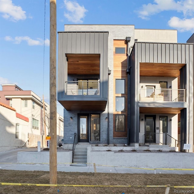view of front of home with brick siding and a balcony