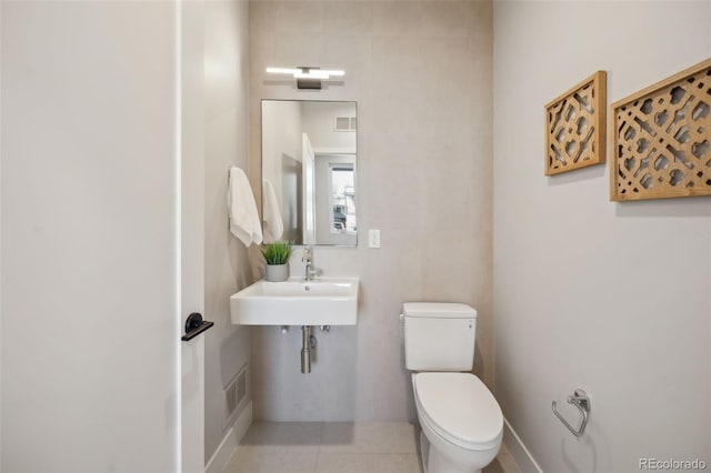 bathroom with toilet, tile patterned flooring, visible vents, and a sink