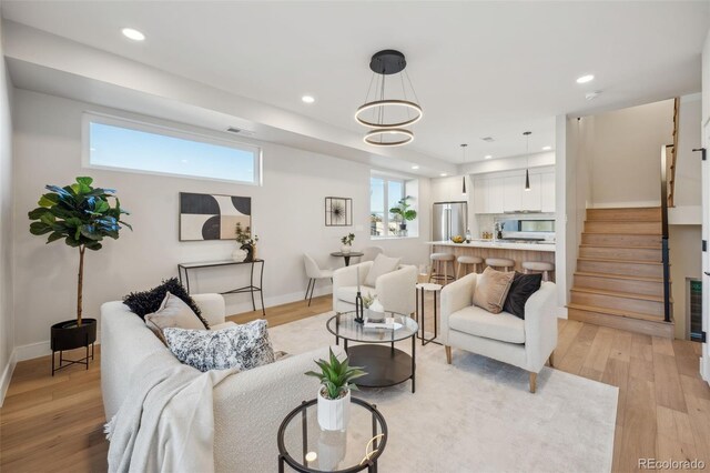 living room featuring stairway, light wood-style flooring, a healthy amount of sunlight, and recessed lighting