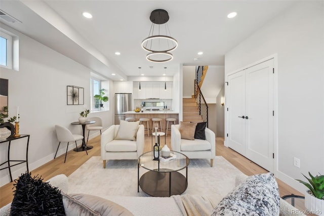 living area with stairway, light wood finished floors, plenty of natural light, and visible vents