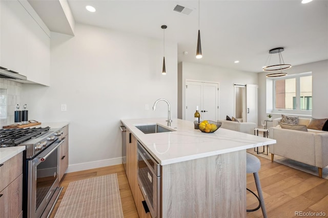 kitchen featuring modern cabinets, visible vents, a sink, a kitchen breakfast bar, and stainless steel appliances