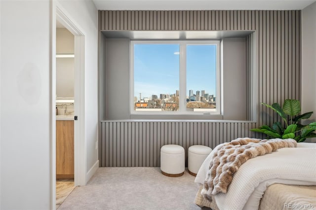 bedroom with carpet flooring, ensuite bathroom, and a city view