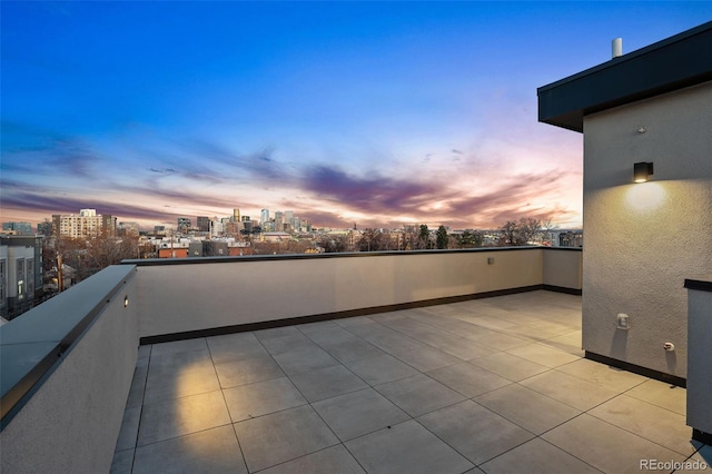 patio terrace at dusk with a view of city and a balcony