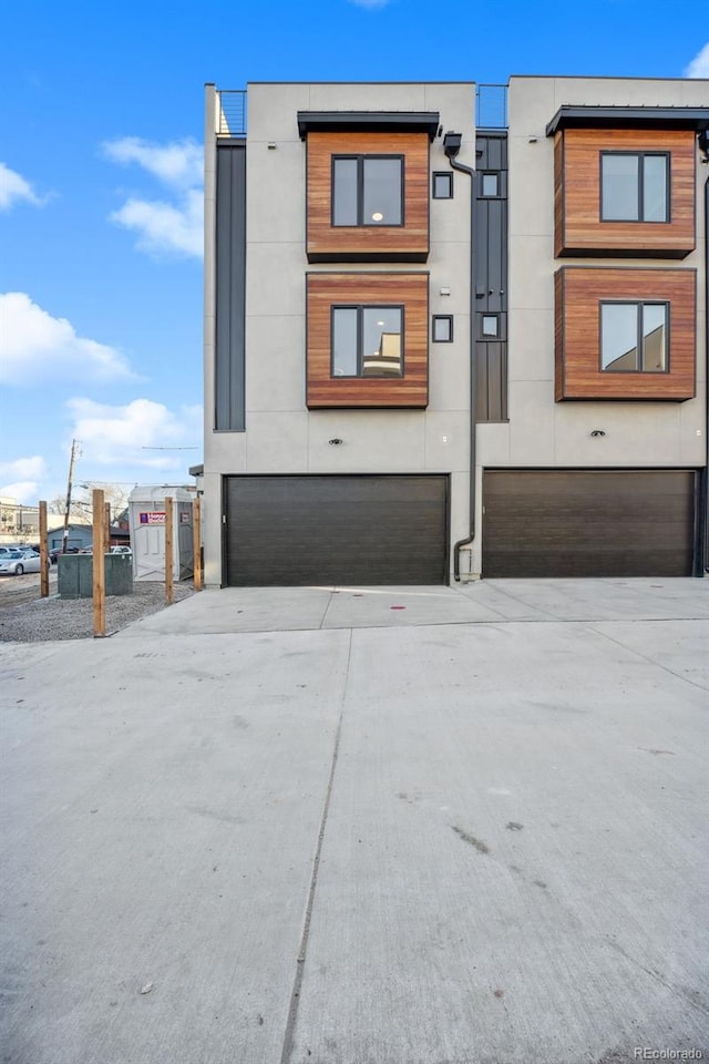 view of front facade featuring concrete driveway, a garage, and stucco siding