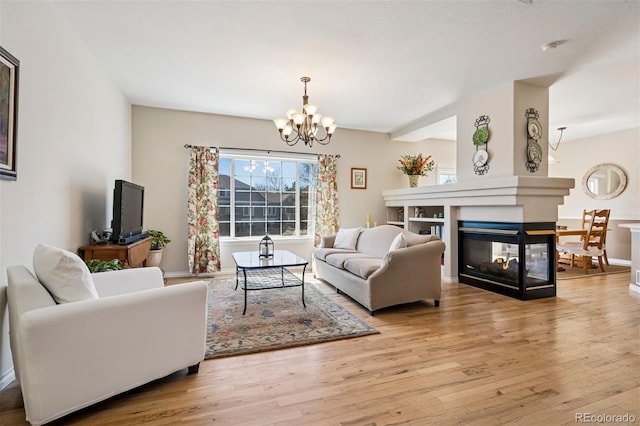 living room with a chandelier, wood finished floors, a multi sided fireplace, and baseboards