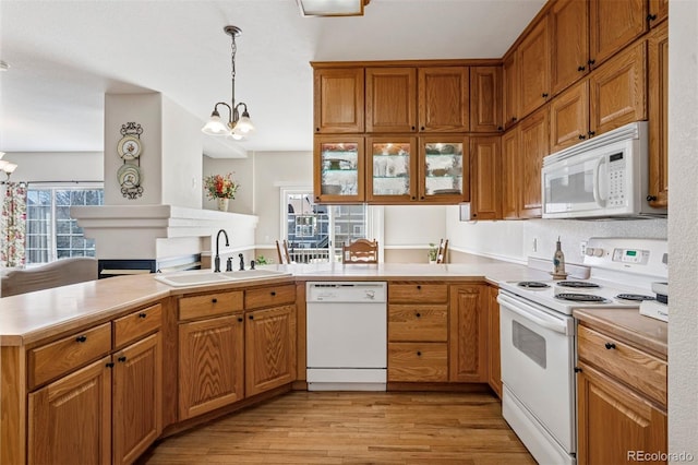 kitchen featuring white appliances, a sink, a chandelier, and a peninsula