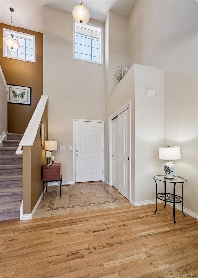 entrance foyer with a towering ceiling, baseboards, plenty of natural light, and stairway