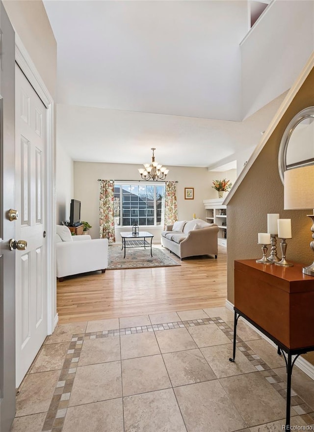 hall with light tile patterned flooring, a chandelier, inlaid floor details, and baseboards