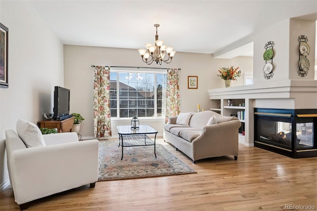 living area with a chandelier, a multi sided fireplace, wood finished floors, and baseboards