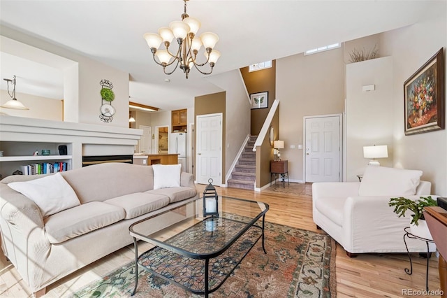 living room featuring a chandelier, stairway, light wood-style flooring, and baseboards