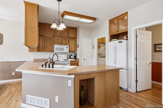 kitchen with white appliances, light wood-type flooring, baseboards, a peninsula, and a chandelier
