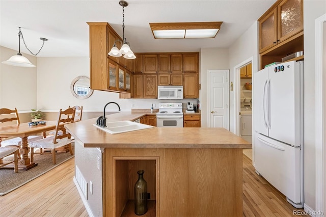 kitchen featuring white appliances, a sink, light wood-style floors, a peninsula, and glass insert cabinets