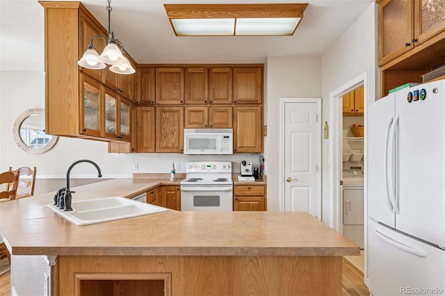 kitchen featuring white appliances, a sink, a peninsula, washer / clothes dryer, and light countertops