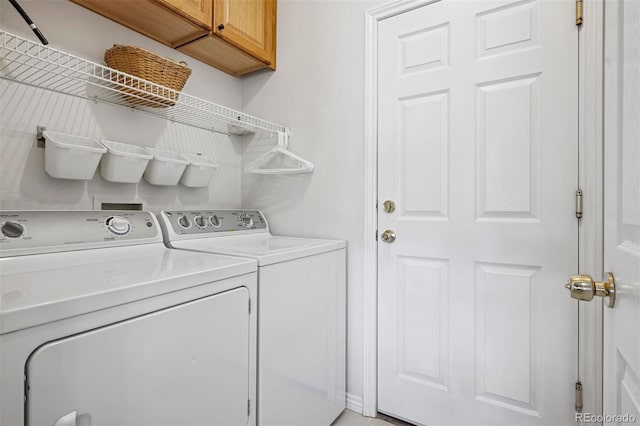 clothes washing area featuring washing machine and clothes dryer and cabinet space