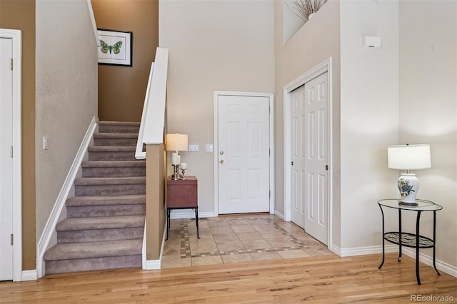 entrance foyer featuring baseboards, stairway, a high ceiling, and wood finished floors