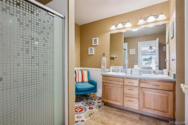 full bath featuring a shower stall, double vanity, tile patterned floors, and wainscoting
