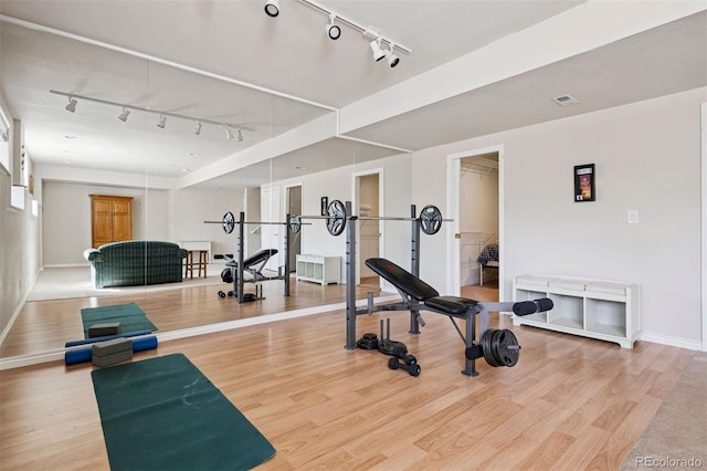 exercise area featuring track lighting, wood finished floors, and baseboards