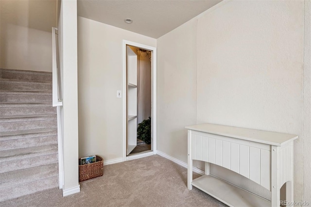carpeted entryway with stairs and baseboards