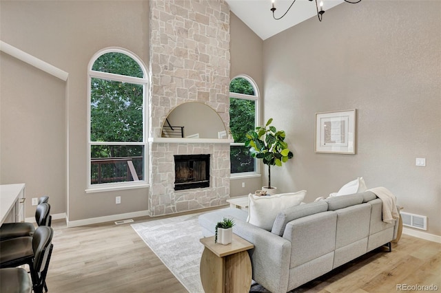 9371 Princeton Ln, Highlands Ranch, CO 80130 - living area featuring high vaulted ceiling, light wood-style flooring, a stone fireplace, and a chandelier
