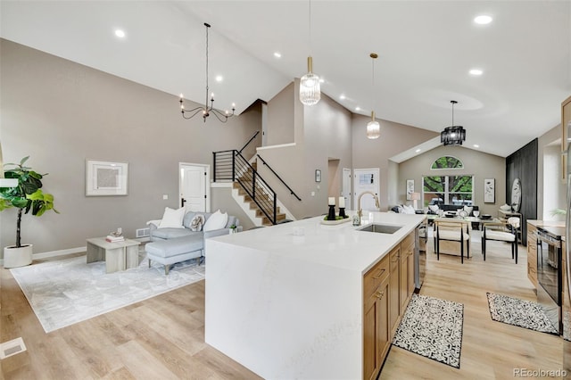 9371 Princeton Ln, Highlands Ranch, CO 80130 - kitchen featuring open floor plan, high vaulted ceiling, light wood-style floors, a center island with sink, and hanging light fixtures