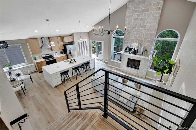 9371 Princeton Ln, Highlands Ranch, CO 80130 - stairs featuring wood finished floors, a chandelier, high vaulted ceiling, and a stone fireplace