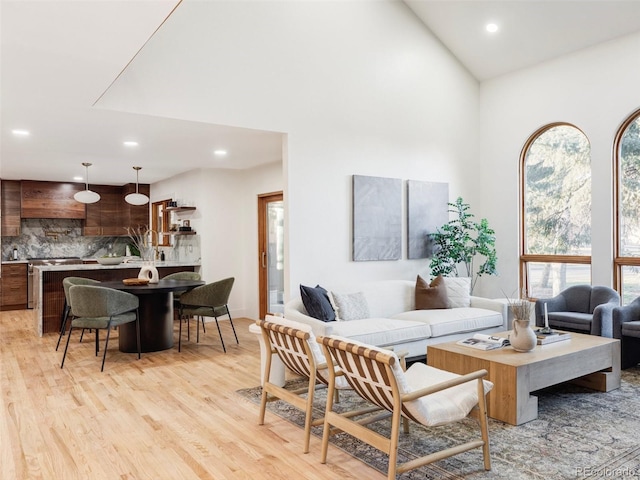 living room featuring high vaulted ceiling, recessed lighting, and light wood-style floors