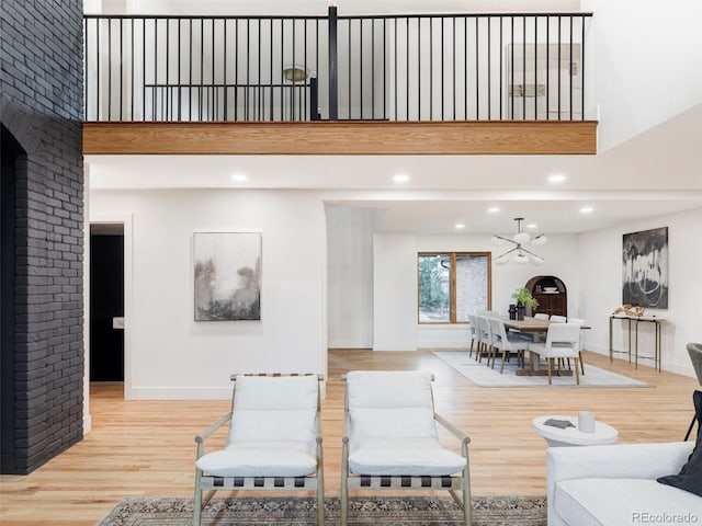 living room featuring a notable chandelier, a high ceiling, baseboards, and wood finished floors