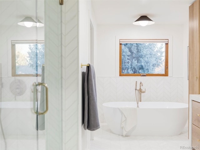 bathroom with a soaking tub, a shower stall, and tile walls