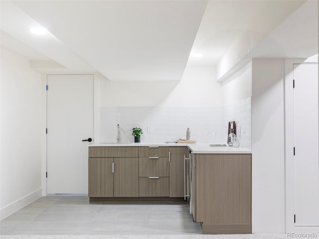 bar with tasteful backsplash, a sink, baseboards, and light tile patterned floors