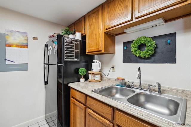 kitchen with black fridge, sink, and light tile patterned floors