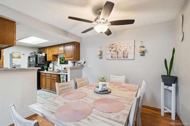 dining area featuring ceiling fan, a textured ceiling, light hardwood / wood-style flooring, and sink